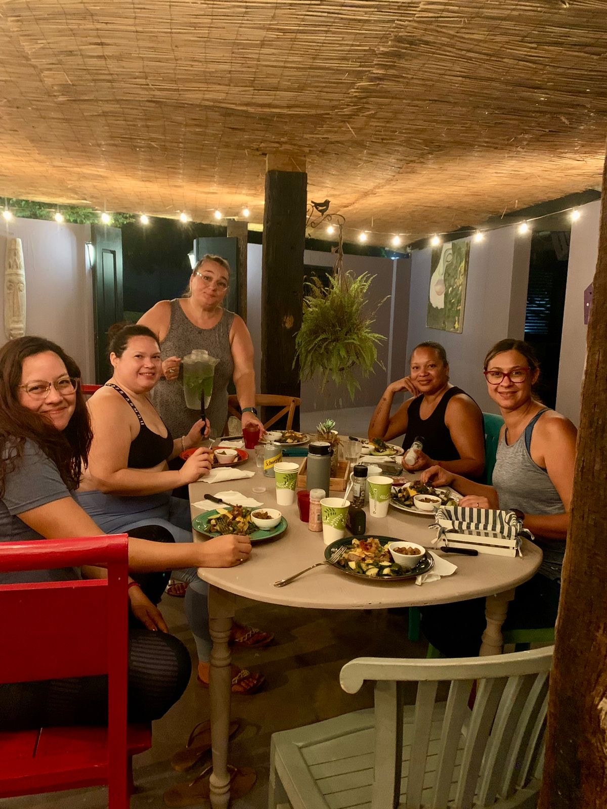 Real group of friends dining and gathering together under warm palapa lights at Mammaloe’s Aruba